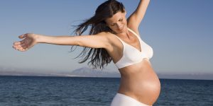 Mujer embarazada disfrutando de su embarazo en el mar